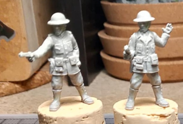 Two unpainted miniature soldier figurines on a work table